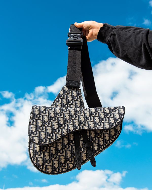 Beige and Black Dior Oblique Jacquard bag held up into the blue sky